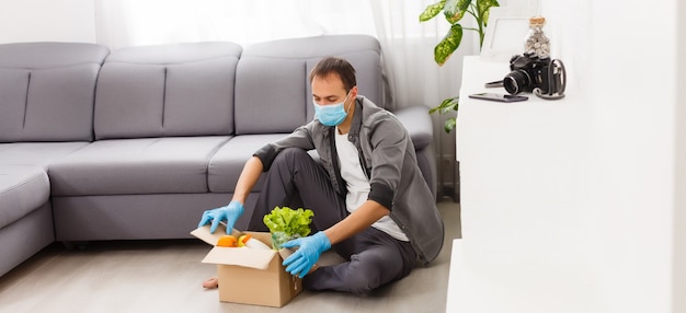 Voluntarios con caja de donación con productos alimenticios sobre fondo gris