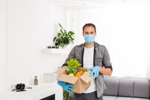 Voluntarios con caja de donación con productos alimenticios sobre fondo gris