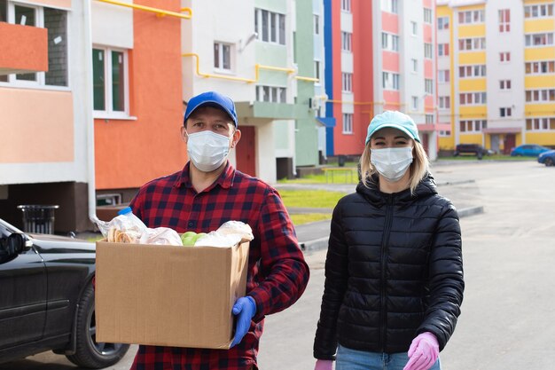 Los voluntarios caminan por la calle con una caja de comestibles.