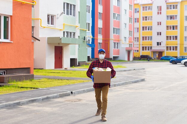 Los voluntarios caminan por la calle con una caja de comestibles.