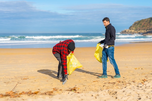 Foto voluntários coletando plástico da areia na praia conceito de ecologia poluição do mar