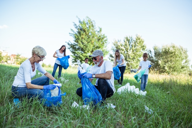 Foto voluntários com sacos de lixo limpando o lixo ao ar livre - conceito de ecologia.