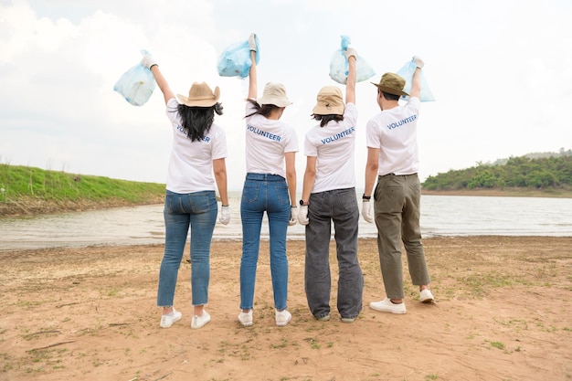 Voluntarios de la comunidad juvenil asiática usando bolsas de basura limpiando la naturaleza