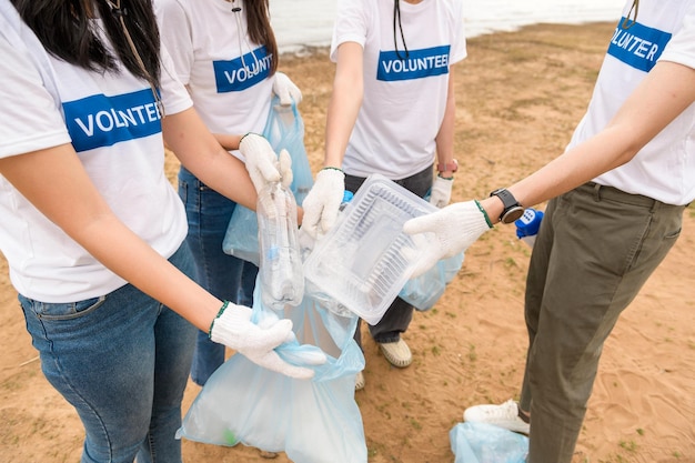 Voluntarios de la comunidad juvenil asiática usando bolsas de basura limpiando la naturaleza