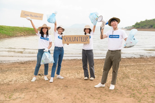 Voluntários da comunidade jovem asiática usando sacos de lixo para limpar a natureza