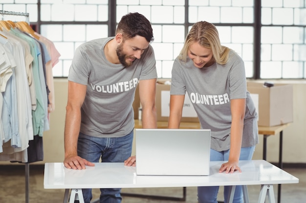 Voluntários discutindo enquanto trabalham no laptop no escritório