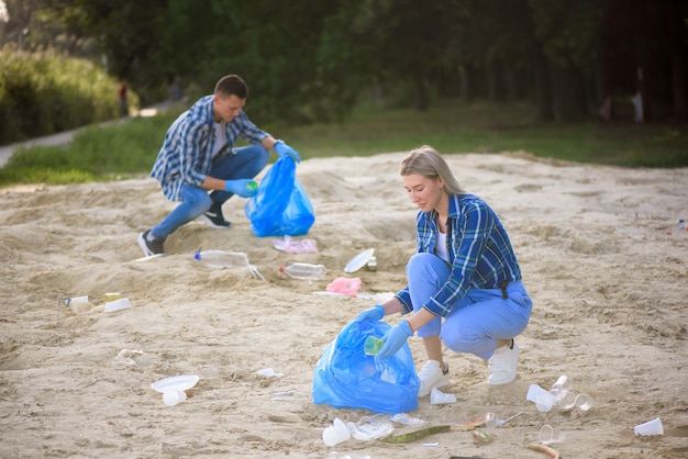 Voluntários felizes com sacos de lixo, limpeza de área no parque