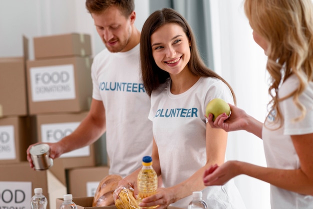 Voluntários sorridentes preparando caixas com doações de alimentos para instituições de caridade