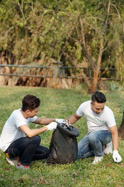 Foto voluteers recogiendo hojas caídas en grandes bolsas de basura en el parque de la ciudad