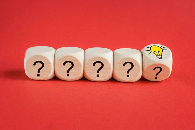 Volver una bombilla encendida y un signo de interrogación en un cubo de madera para el pensamiento creativo