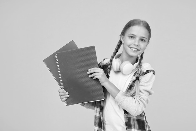 Volver a la escuela usar cuaderno o libro Estudiar lecciones para el examen encontrar inspiración en el libro Disfrutar del estudio Confía en su conocimiento niño pequeño en auriculares con bloc de notas niño listo para estudiar