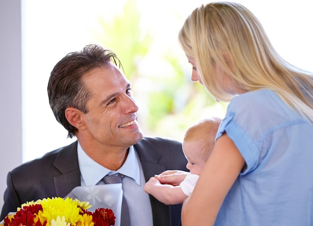 Volviendo a casa con flores padres y bebé en una casa con amor apoyo y unión con gratitud feliz ramo de familia y hombre de negocios con sorpresa floral para la primera celebración del día de la madre