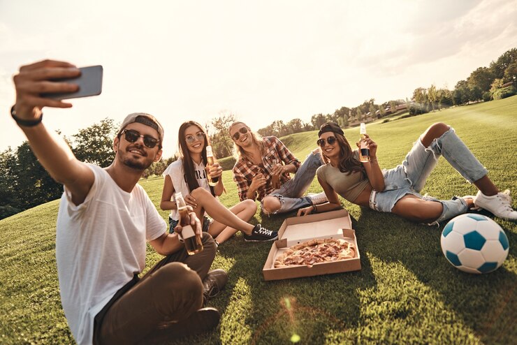 Foto volviéndonos locos juntos. grupo de jóvenes sonrientes en ropa casual tomando selfie mientras disfruta de alimentos y bebidas al aire libre