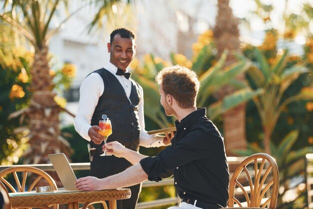 Vom Kellner bedient Junger Mann ist tagsüber im Freien Konzept des Urlaubs