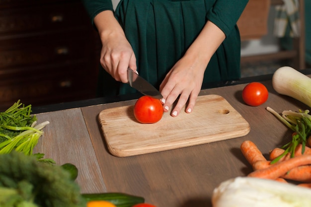 Von einer Frau wird am Tisch eine Tomate geschnitten