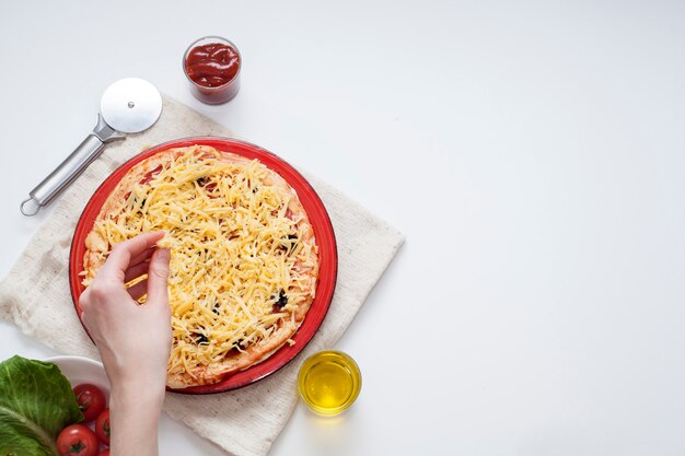 Von Hand Käse auf Pizza mit Salami streuen