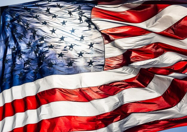 Foto von hinten beleuchtete amerikanische flagge weht im wind vor einem tiefblauen himmel