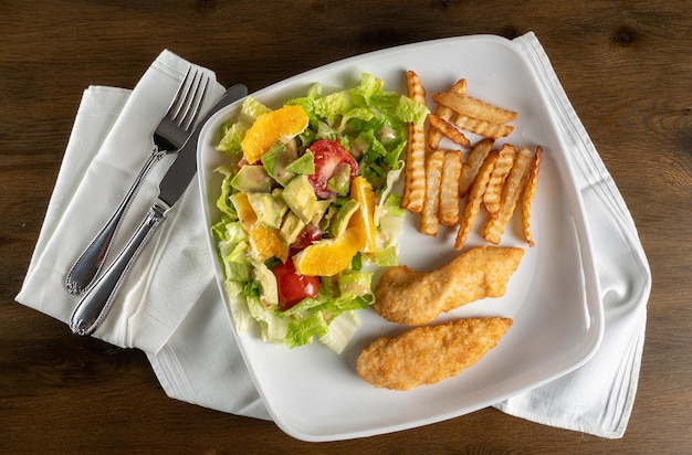 Von oben Blick auf hausgemachte Salatchips und Hühnchentender oder Nuggets, die zu Hause mit Serviette überzogen sind