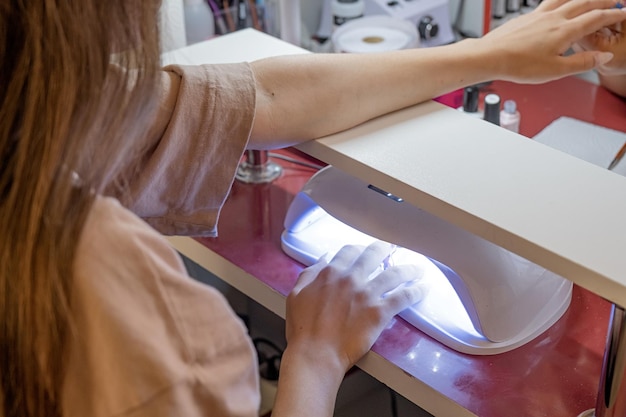 Foto von oben der ernte unerkennbare maniküristin macht nagelkunst für weibliche kunden im schönheitssalon