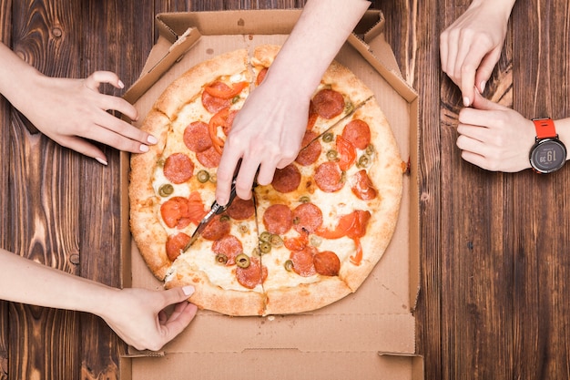 Foto von oben die hand, die pizza trennt