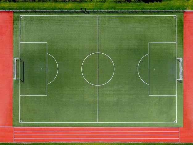 Von oben Luftaufnahme des leeren grünen Fußballplatzes mit weißen Linien und Toren auf dem Sportstadion am Sommertag