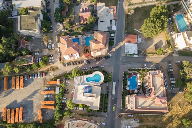 Von oben nach unten Luftaufnahme der Hoteldächer, Straßen mit geparkten Autos und Schwimmbäder mit blauem Wasser in der Kurstadt in der Nähe des Meeres.