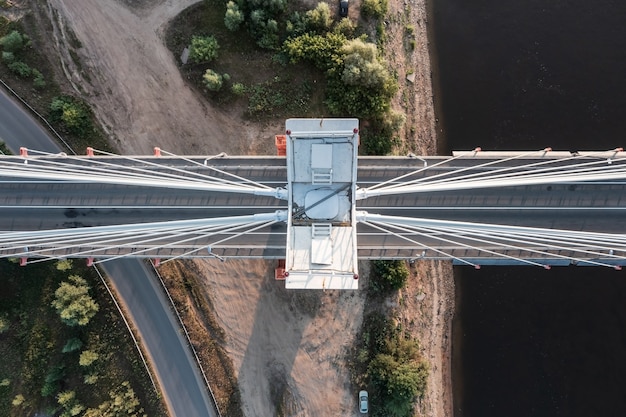 Von oben nach unten Luftaufnahme einer Säule der weißen Hängebrücke, die auf einem Flussufer steht