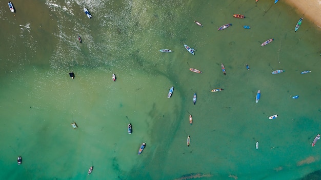 Von oben nach unten luftbild-drohne-kamera des wunderschönen türkisfarbenen klaren wassermeeres mit fischerbooten mit langem schwanz im sommermeer tropische insel phuket im süden thailands erstaunliche seelandschaft vogelperspektive.