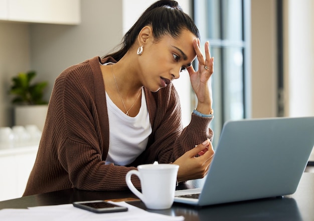 Von zu Hause aus zu arbeiten ist an manchen Tagen sicher eine Qual Aufnahme einer jungen Frau, die gestresst aussieht, während sie zu Hause an ihrem Laptop arbeitet