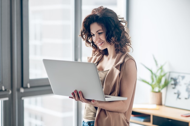 Von zuhause aus arbeiten. Dunkelhaarige hübsche Frau, die an einem Laptop arbeitet und konzentriert aussieht