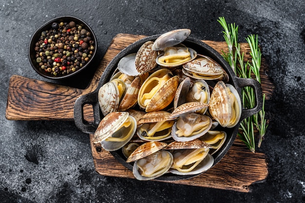 Vongole de almejas cocidas en una sartén. Fondo negro. Vista superior.