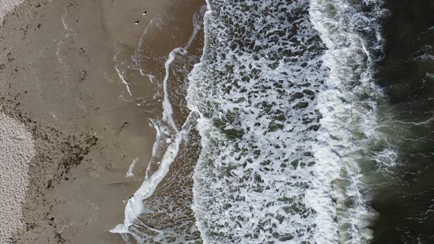 Vôo aéreo de drones sobre belas ondas do mar e espuma branca na praia de areia vista superior do fantástico