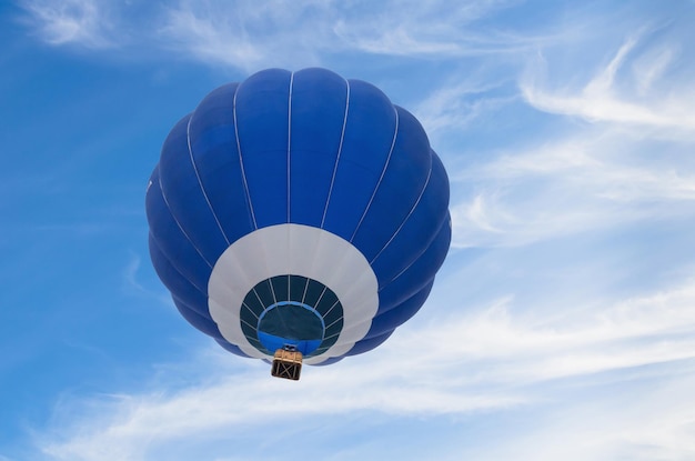 Voo de balão de ar quente azul sobre o céu azul com nuvens brancas