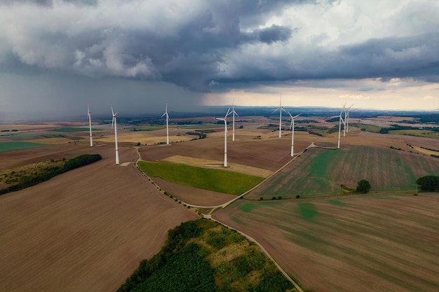 Foto vôo de drone em alta altitude sobre um grande campo com muitas turbinas eólicas girando as turbinas eólicas