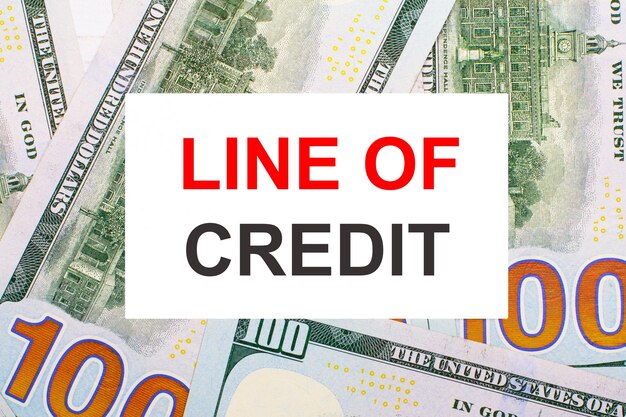 Vor dem Hintergrund des amerikanischen Dollars eine weiße Karte mit dem Finanzkonzept LINE OF CREDIT