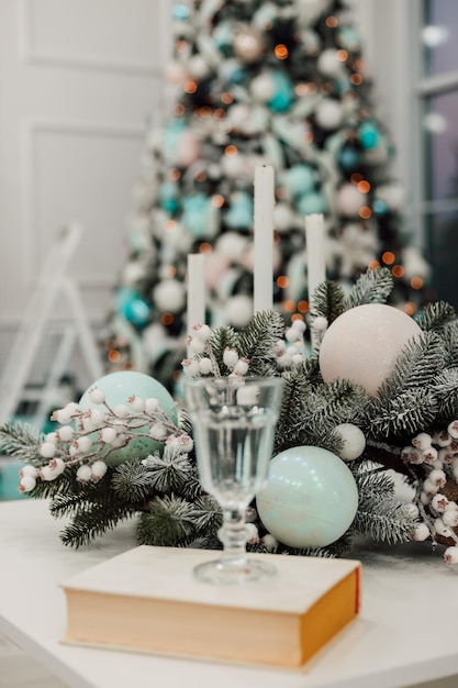 Vor dem Hintergrund des Weihnachtsbaumes steht ein Glas Champagner auf dem Tisch