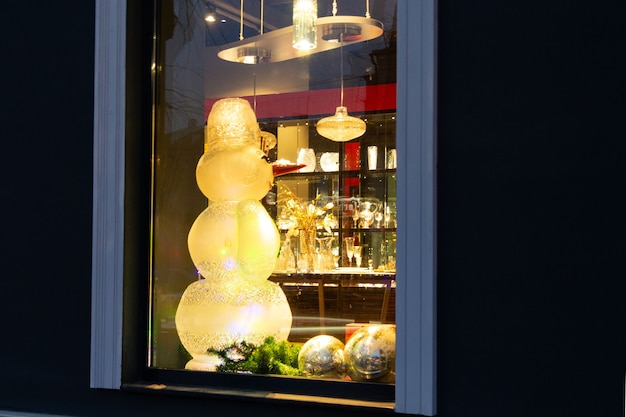 Vor Weihnachten steht ein großer Schneemann aus Glas oder Kristall mit Karotten im Schaufenster.