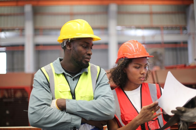 Vorarbeiter oder Arbeiter arbeiten am Fabrikstandort und überprüfen Maschinen oder Produkte vor Ort. Ingenieur oder Techniker überprüfen Material oder Maschine in der Industrie- und Fabrikanlage