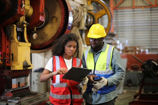 Vorarbeiter oder Arbeiter arbeiten am Fabrikstandort und überprüfen Maschinen oder Produkte vor Ort. Ingenieur oder Techniker überprüfen Material oder Maschine in der Industrie- und Fabrikanlage