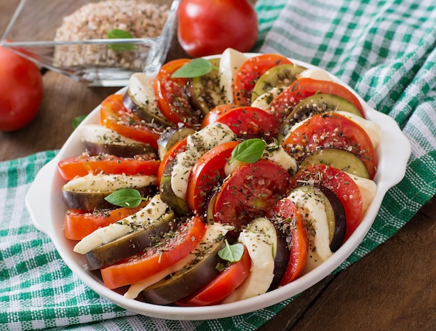 Vorbereitete Auflaufform rohe Auberginen mit Mozzarella und Tomaten