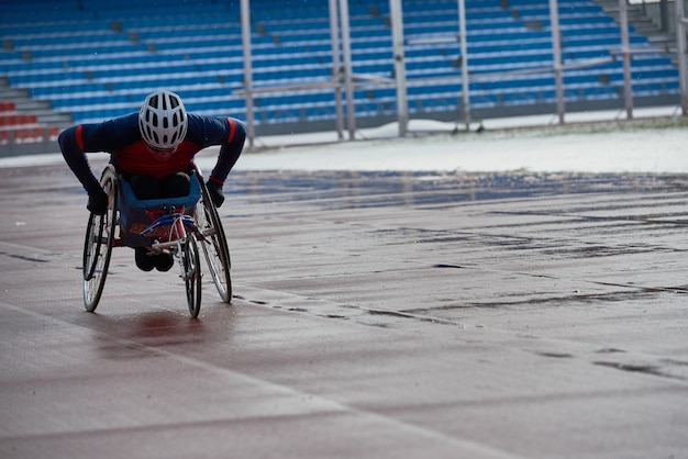 Foto vorbereitung auf den rollstuhlmarathon. entschlossener querschnittsgelähmter sportler, der im handrad im leichtathletikstadion im freien am düsteren regnerischen nachmittag fährt