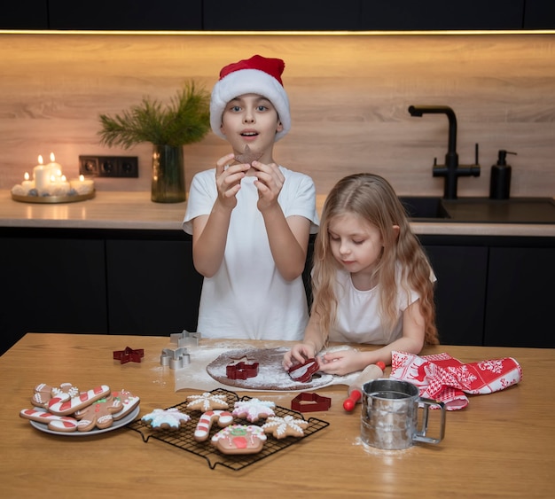 Vorbereitung auf die Weihnachtsferien. Kinder - ein Junge und ein Mädchen bereiten in der Küche Lebkuchen zu