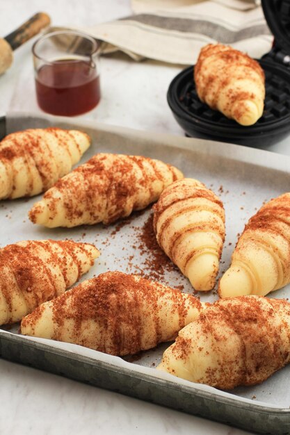 Foto vorbereitung der croffle-beschichtung von rohem croissant-teig mit palmzucker und zimtpulver