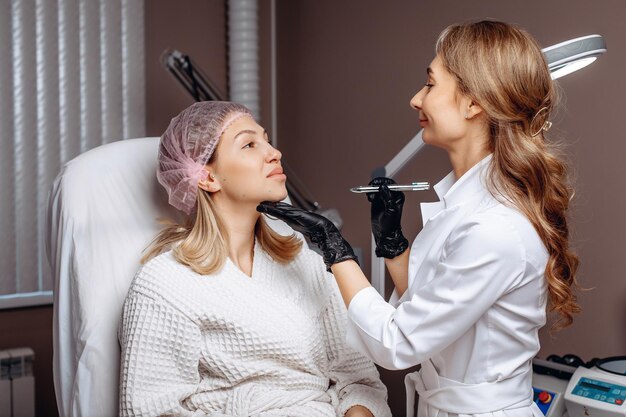 Vorbereitung der Gesichtshaut für den Eingriff zur Verbesserung durch Anbringen von Markierungen an einer jungen Frau durch eine erfahrene Kosmetikmeisterin