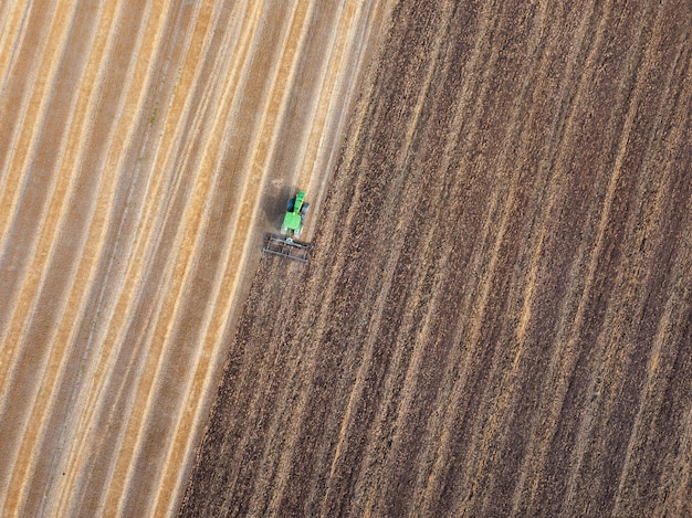 Vorbereitung der landwirtschaftlichen Flächen für die Aussaat, Bodenbearbeitung mit einem Traktor nach der Ernte. Luftaufnahme von der fliegenden Drohne