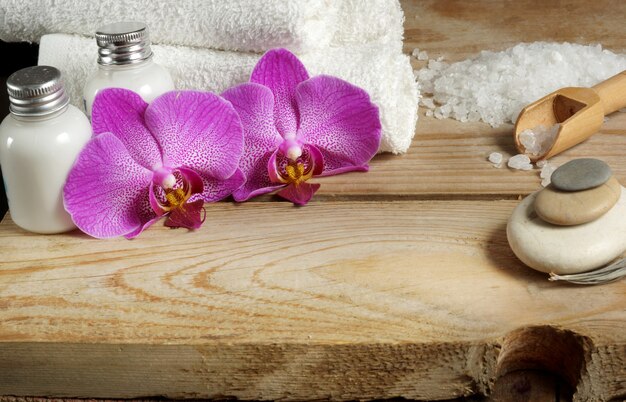 Vorbereitung für Spa-Behandlungen, Salz, Handtücher, Lotion und helle Orchideenblüten