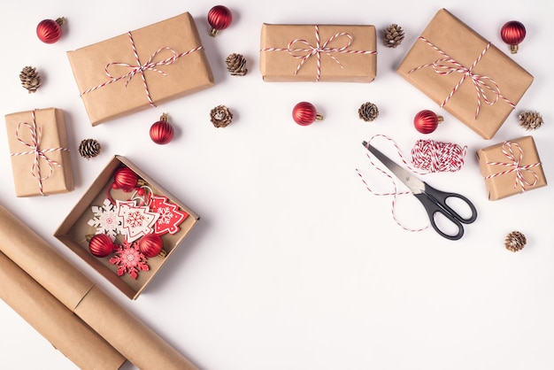 Vorbereitung für Weihnachtskonzept. Oben über dem Overhead Nahaufnahmefoto von Zubehör zum Verpacken von Geschenkboxen, die auf weißem Schreibtischhintergrund liegen