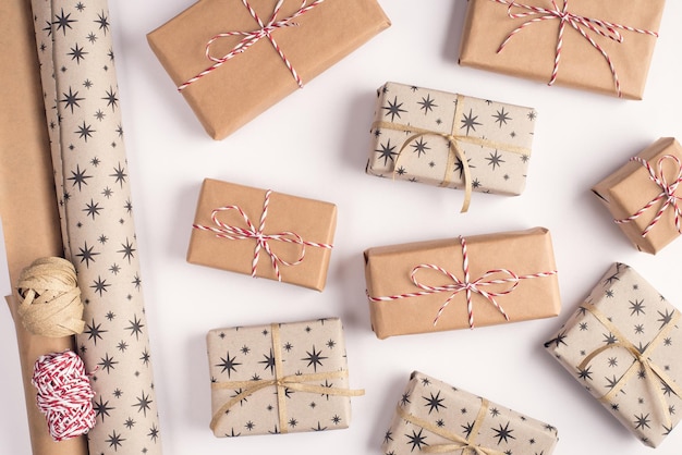 Foto vorbereitung präsentiert konzept. oben über dem kopf nahaufnahme foto von haufen stapel von in kraftpapier eingewickelten geschenken und rollen geschenkpapier mit seilband isoliert auf weißem hintergrund