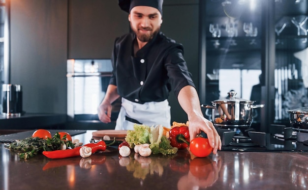 Vorbereitungsprozess Professioneller junger Küchenchef in Uniform, der in der Küche arbeitet