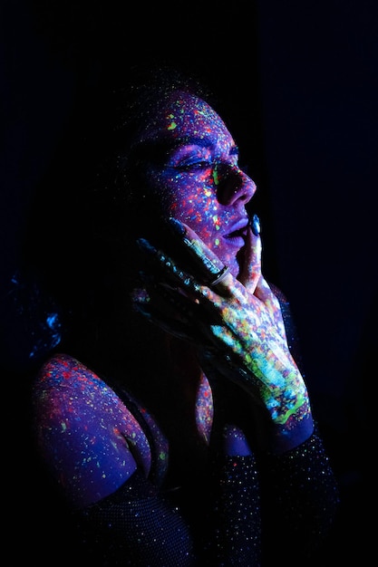 Vorbildliche Frau im Neonlicht Schönes vorbildliches Mädchen mit fluoreszierendem Make-up-Kunstdesign der Disco-Tänzerin, die im bunten Make-up des UV-Lichts tanzt Nachtclub-Party